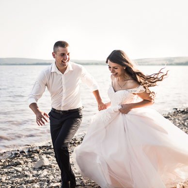 bride-and-groom-laughing-run-together-against-rays-2022-02-14-21-39-48-utc.jpg